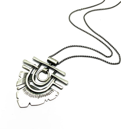 A silver necklace with a geometric-patterned pendant resembling flame 