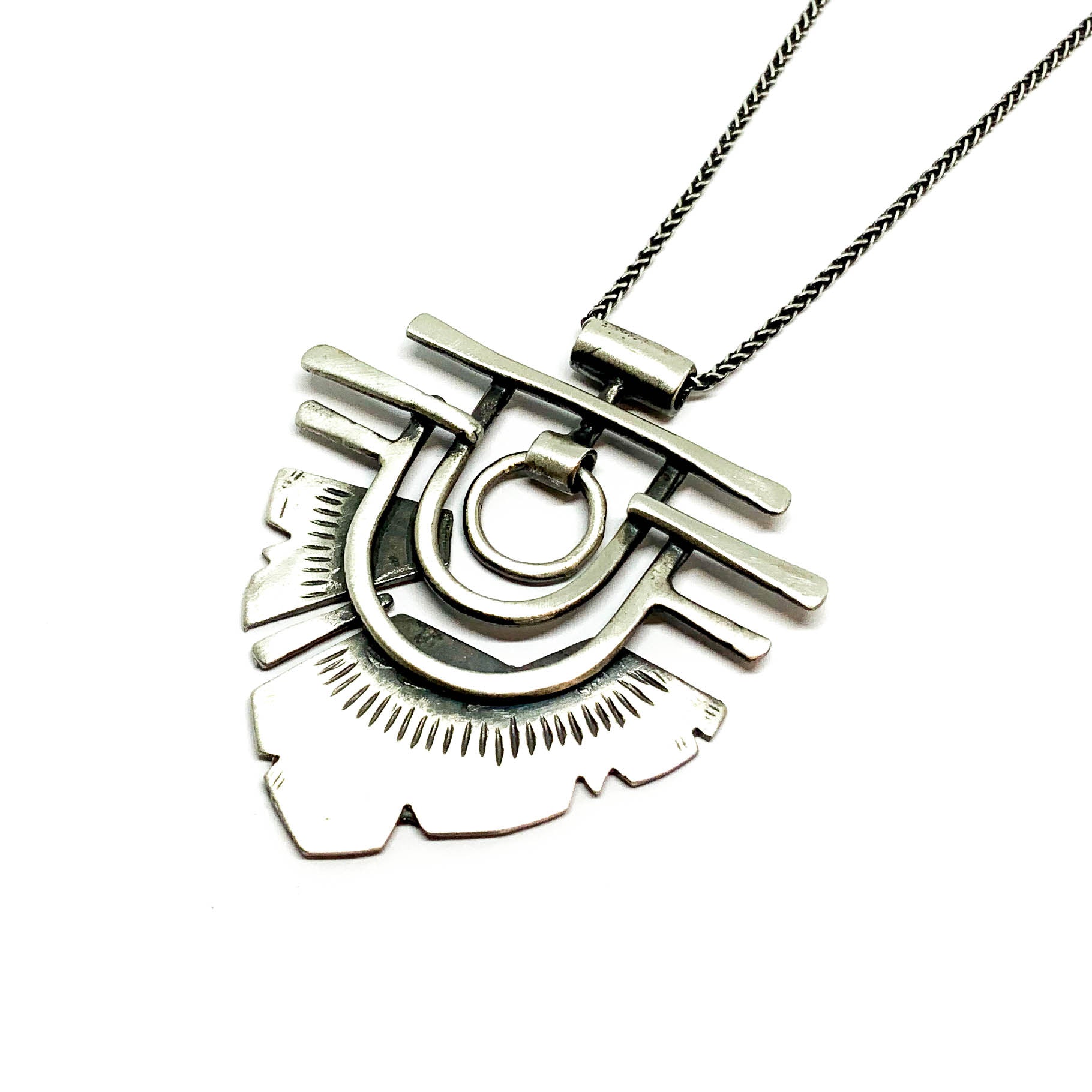 A silver necklace with a geometric-patterned pendant resembling flame 