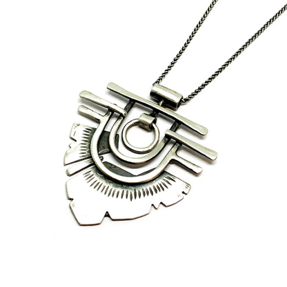 A silver necklace with a geometric-patterned pendant resembling flame 