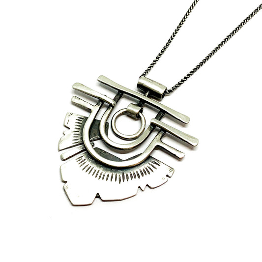 A silver necklace with a geometric-patterned pendant resembling flame 