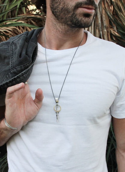 A silver necklace with a pendant featuring a ladder shape and a small cow symbol in the center