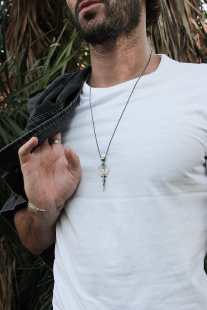 A silver necklace with a pendant featuring a ladder shape and a small cow symbol in the center