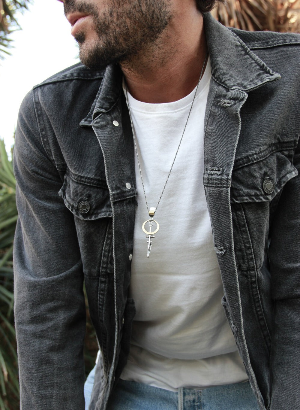 A silver necklace with a pendant featuring a ladder shape and a small cow symbol in the center
