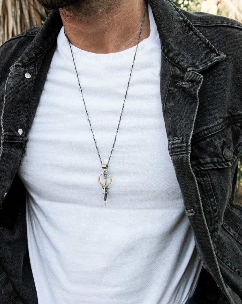 A silver necklace with a pendant featuring a ladder shape and a small cow symbol in the center