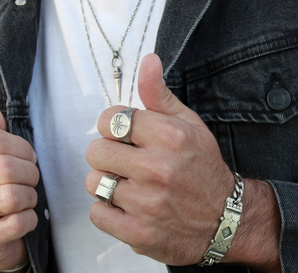 men wearing oasis ring, carved memo ring and a silver bracelet