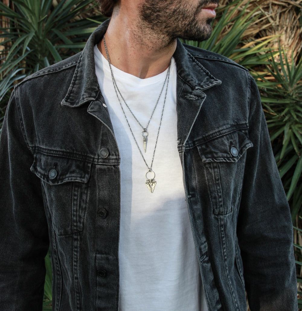 A sterling silver necklace with an oxidized and brushed finish, featuring a pendant with a strength symbol design.