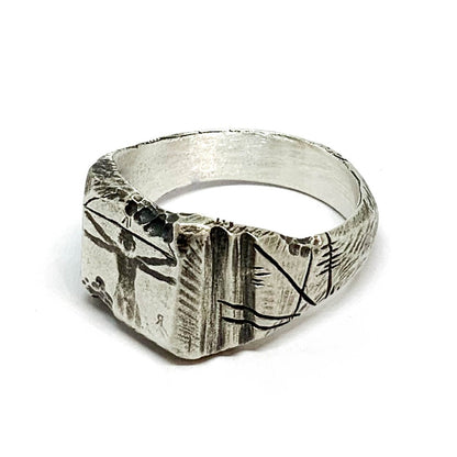 A silver ring with an oxidized and brushed finish, featuring an engraved design inspired by Florentine art, including figures and architectural elements.
