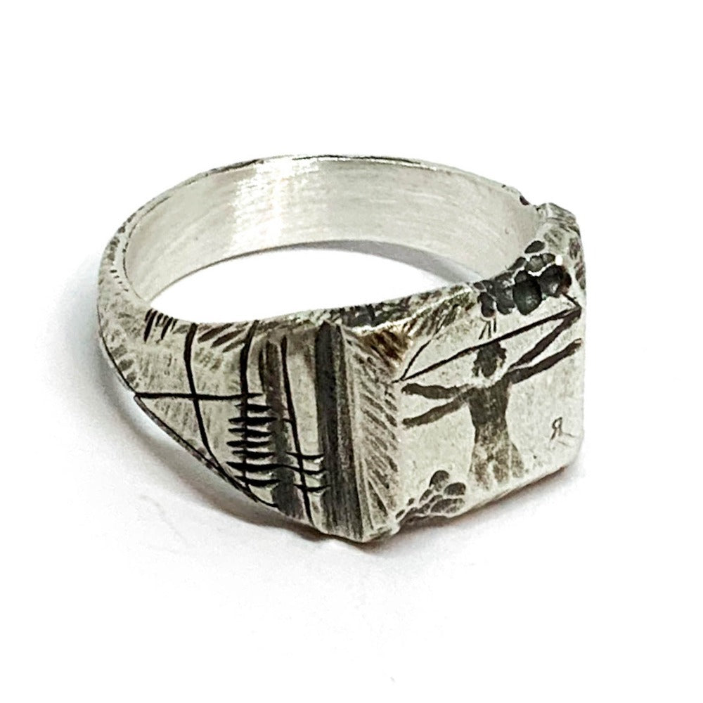 A silver ring with an oxidized and brushed finish, featuring an engraved design inspired by Florentine art, including figures and architectural elements.