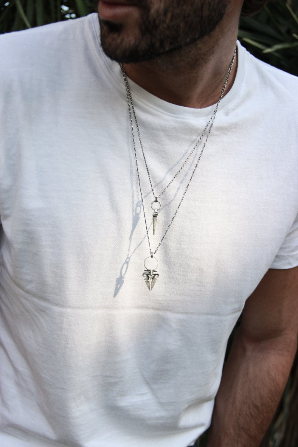 A sterling silver necklace with an oxidized and brushed finish, featuring a pendant with a strength symbol design.