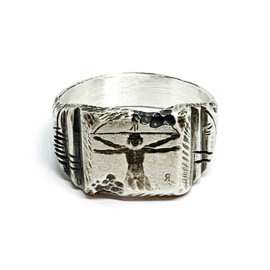 A silver ring with an oxidized and brushed finish, featuring an engraved design inspired by Florentine art, including figures and architectural elements.