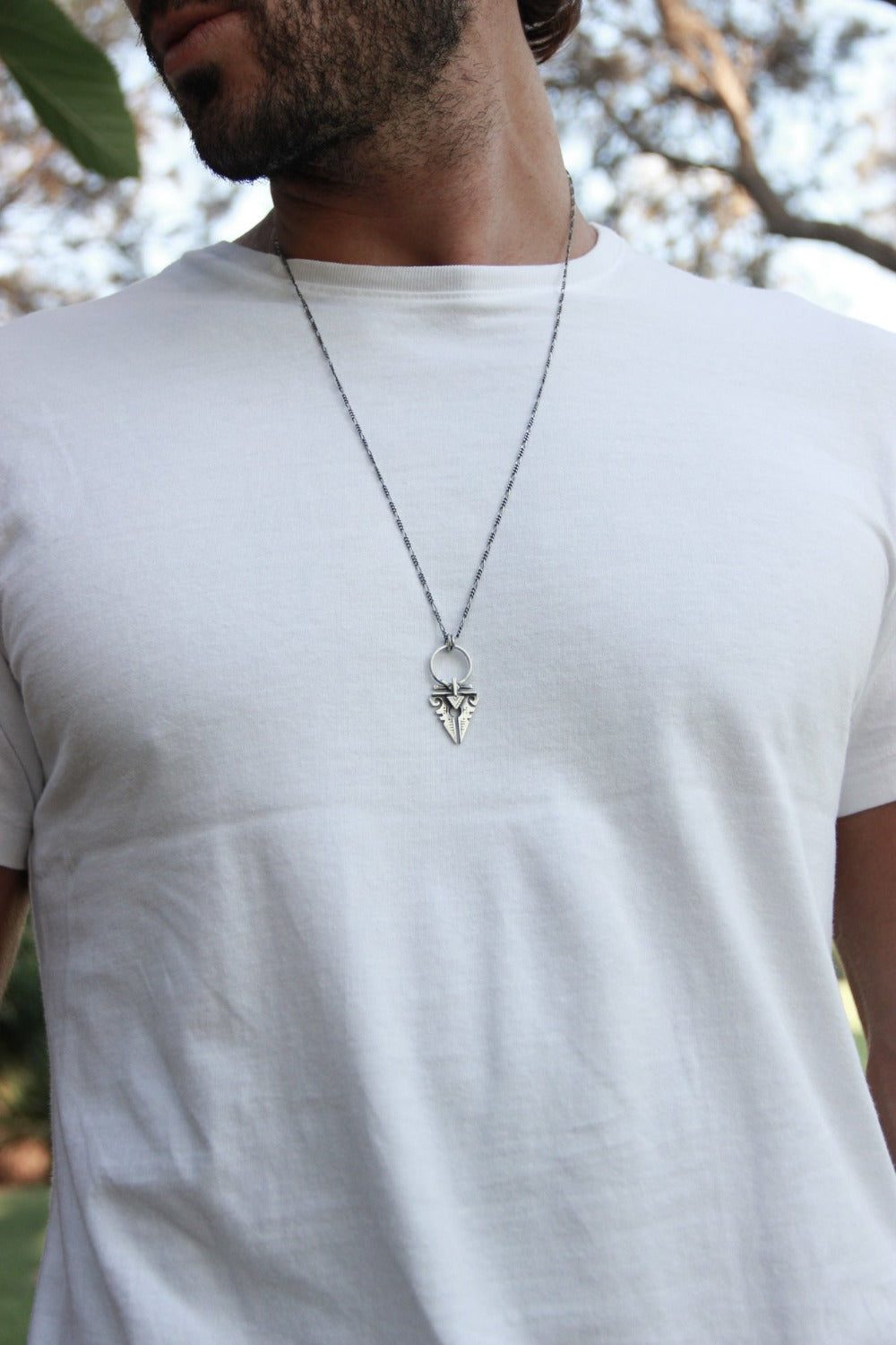 A sterling silver necklace with an oxidized and brushed finish, featuring a pendant with a strength symbol design.