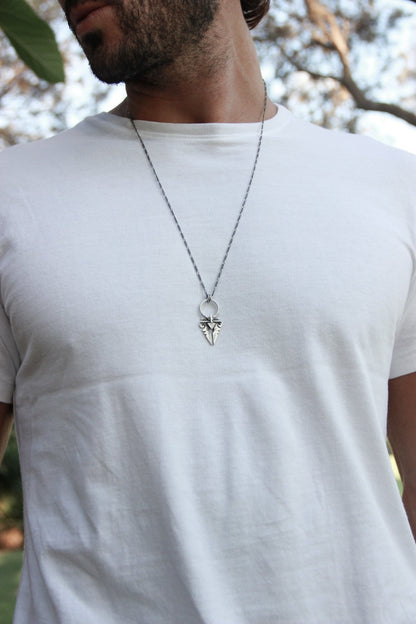 A sterling silver necklace with an oxidized and brushed finish, featuring a pendant with a strength symbol design.