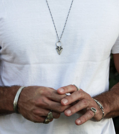 A sterling silver necklace with an oxidized and brushed finish, featuring a pendant with a strength symbol design.
