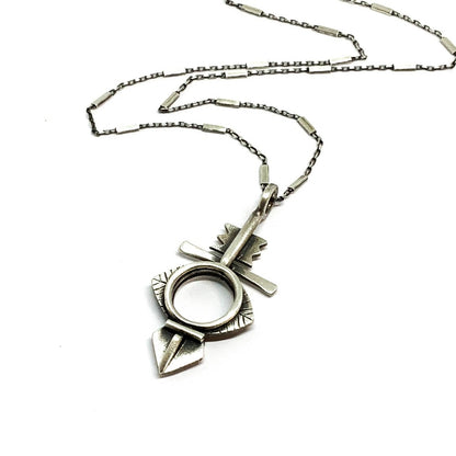A silver necklace with a geometric-patterned pendant, featuring a combination of Morrocan and Mexican inspiration.