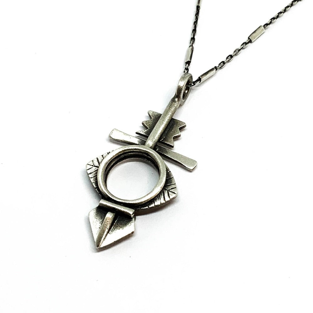 A silver necklace with a geometric-patterned pendant, featuring a combination of Morrocan and Mexican inspiration.