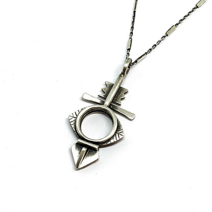 A silver necklace with a geometric-patterned pendant, featuring a combination of Morrocan and Mexican inspiration.
