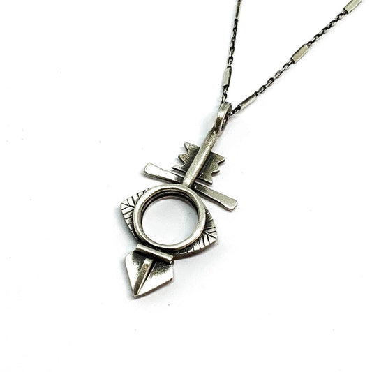 A silver necklace with a geometric-patterned pendant, featuring a combination of Morrocan and Mexican inspiration.