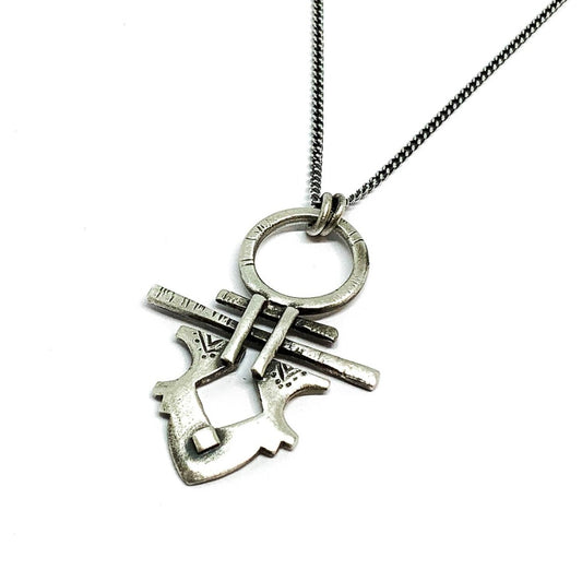 A silver necklace with a pendant featuring a stylized key design, on a white background.