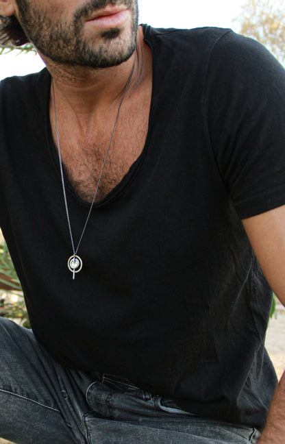 A silver necklace with a pendant featuring a circular design and a chain that ends in a pendant loop.