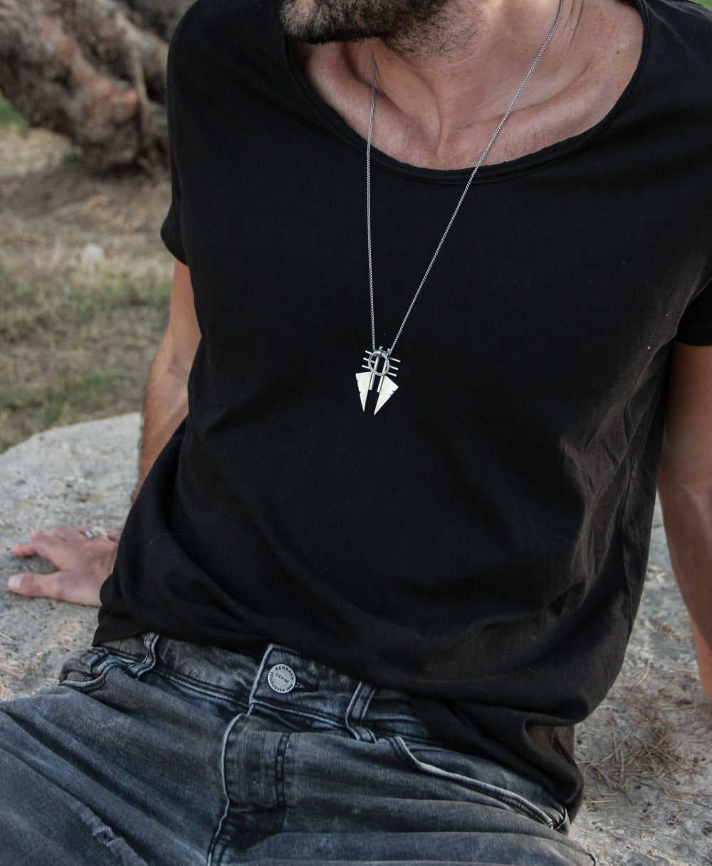 A sterling silver necklace with a pendant featuring two triangles and a circular ornament, with a brushed and oxidized finish.