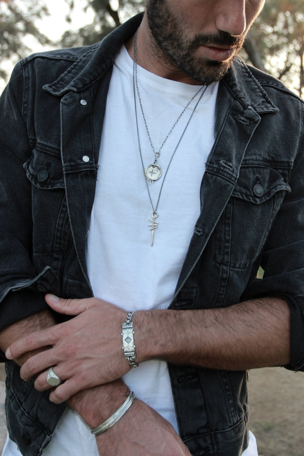 A silver necklace with a pendant featuring a symbol, attached to a chain.