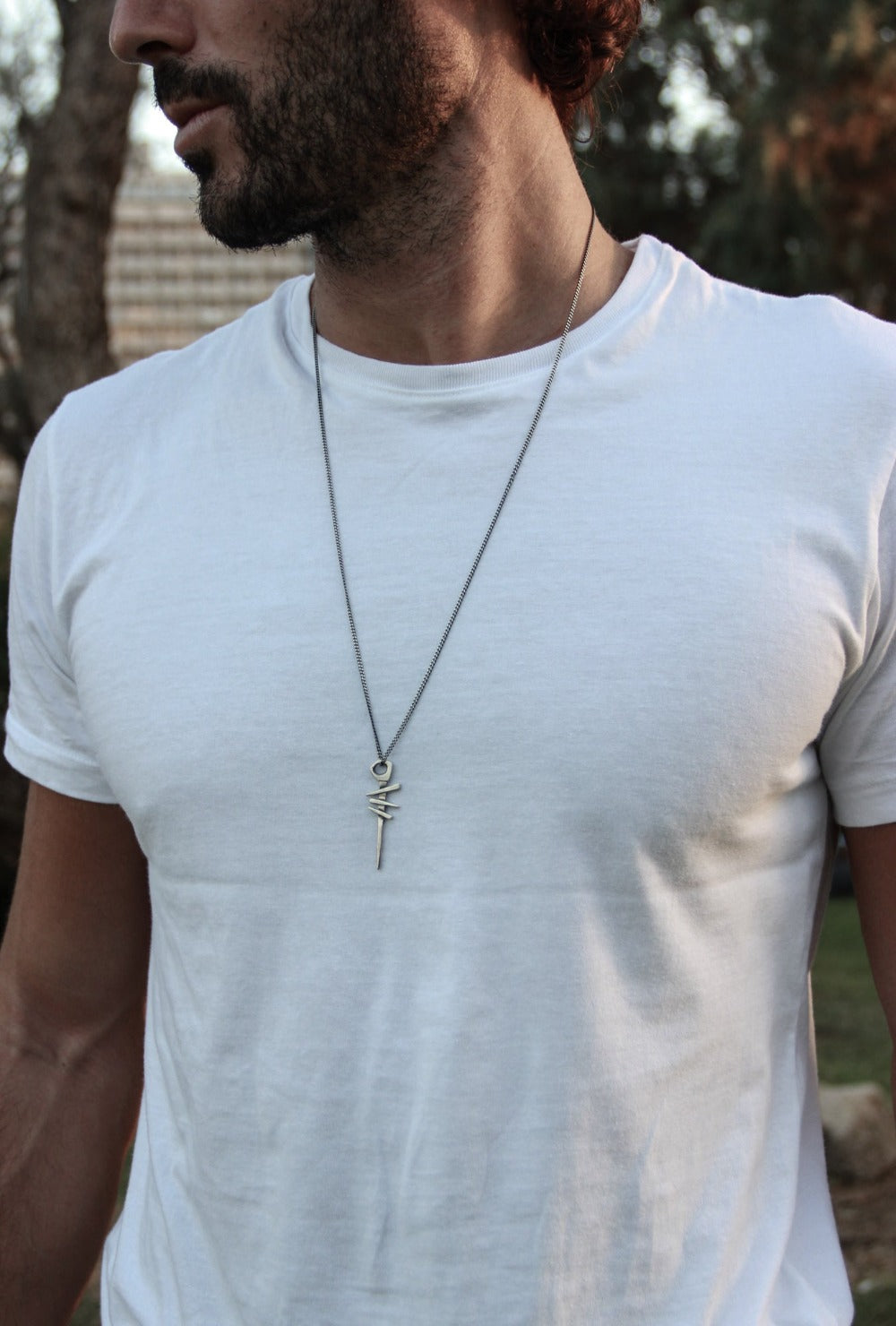 A silver necklace with a pendant featuring a symbol, attached to a chain.