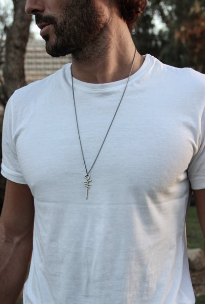 A silver necklace with a pendant featuring a symbol, attached to a chain.