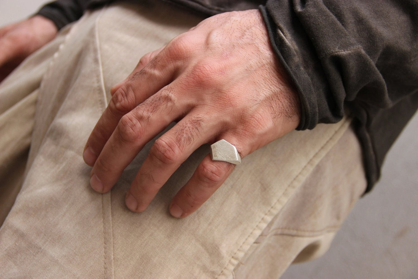 A silver ring with a geometric cutout design on the top part, with a matte finish.