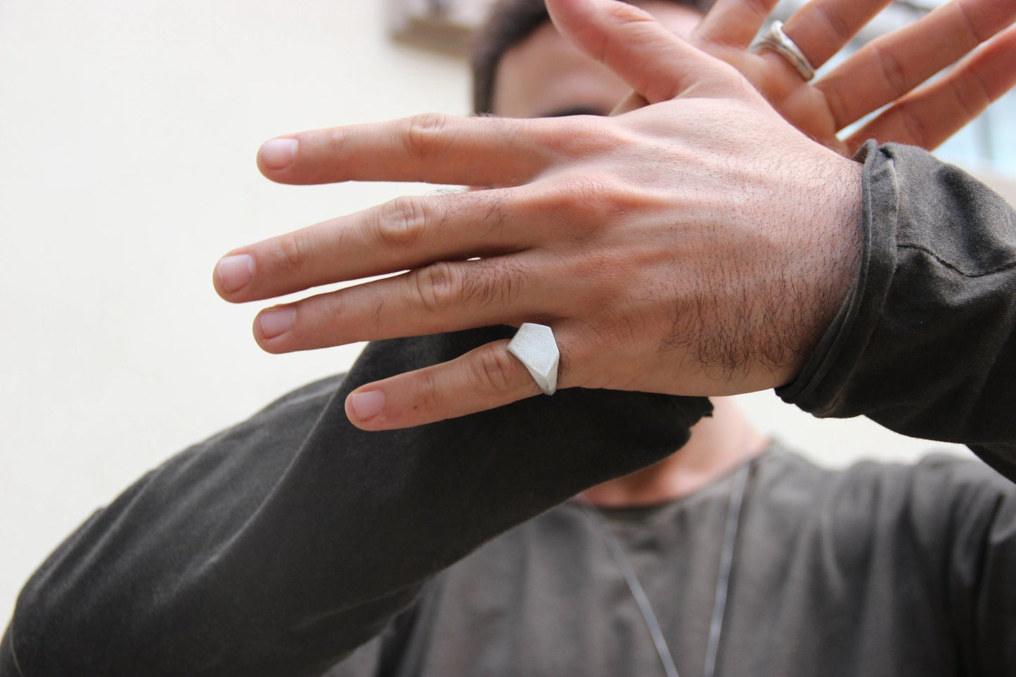 A silver ring with a geometric cutout design on the top part, with a matte finish.