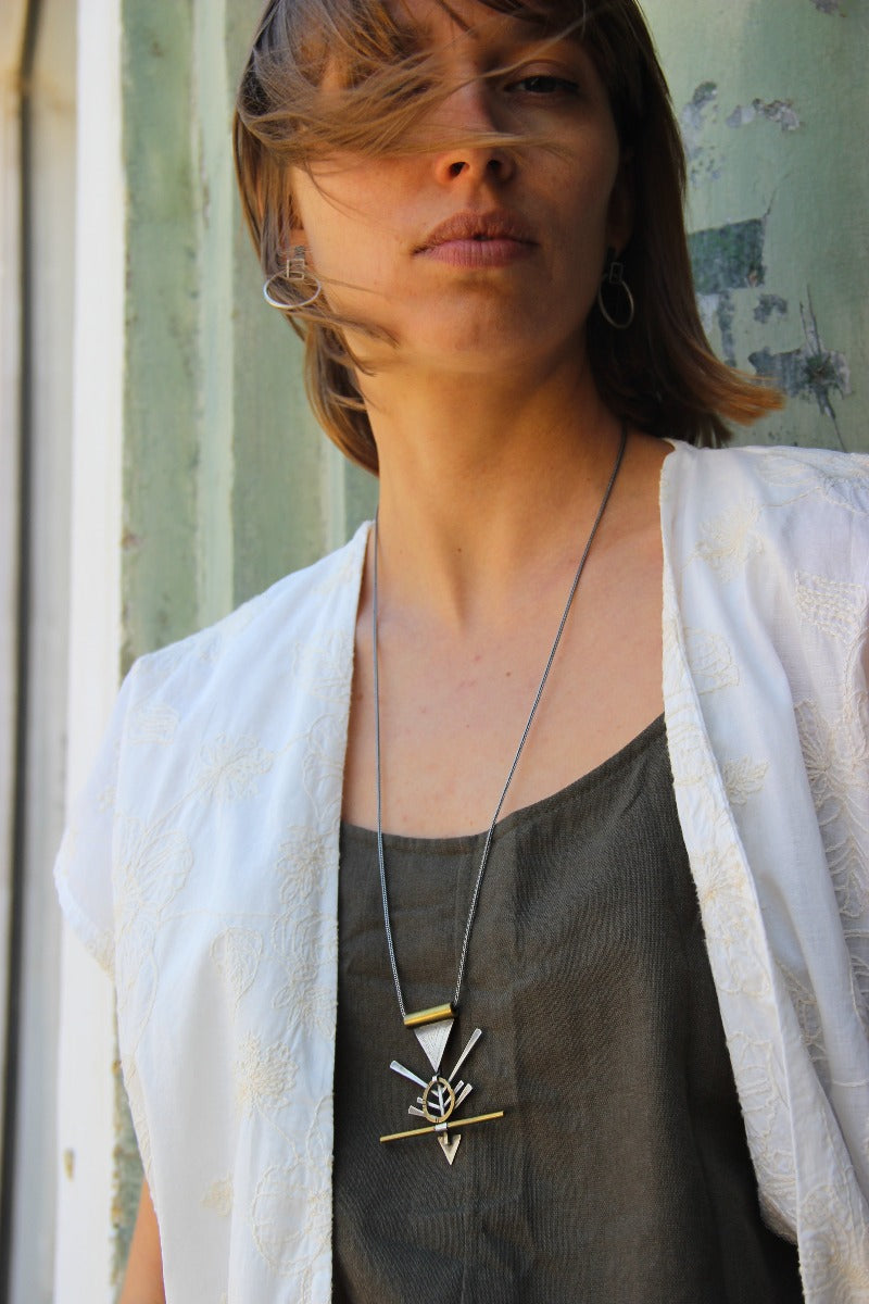 A silver and brass necklace with a geometric pendant, featuring a chain and a series of geometric shaped pendants attached to it.