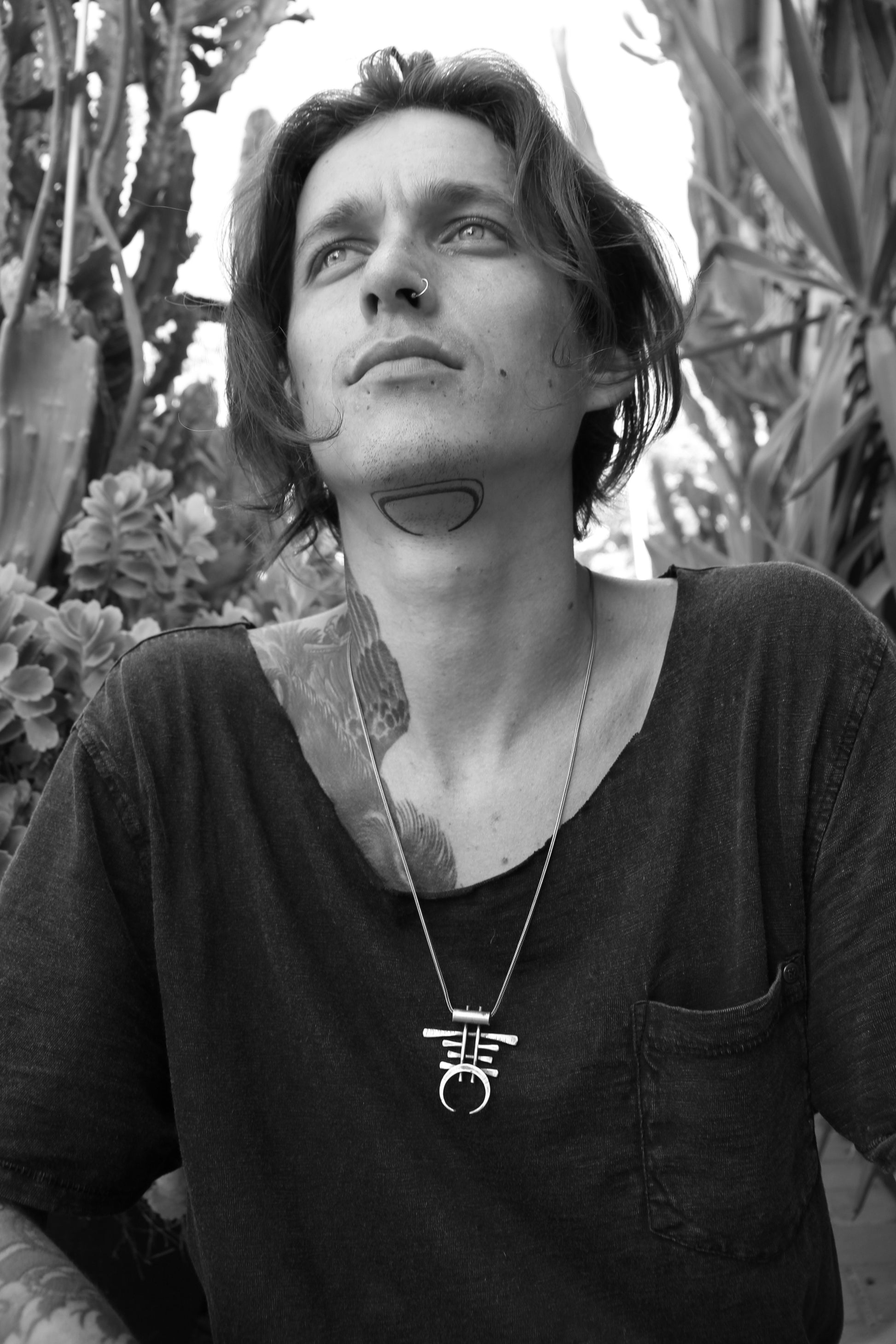 A necklace with a unique geometric pendant made of silver and brass, featuring an oxidized and brushed finish.