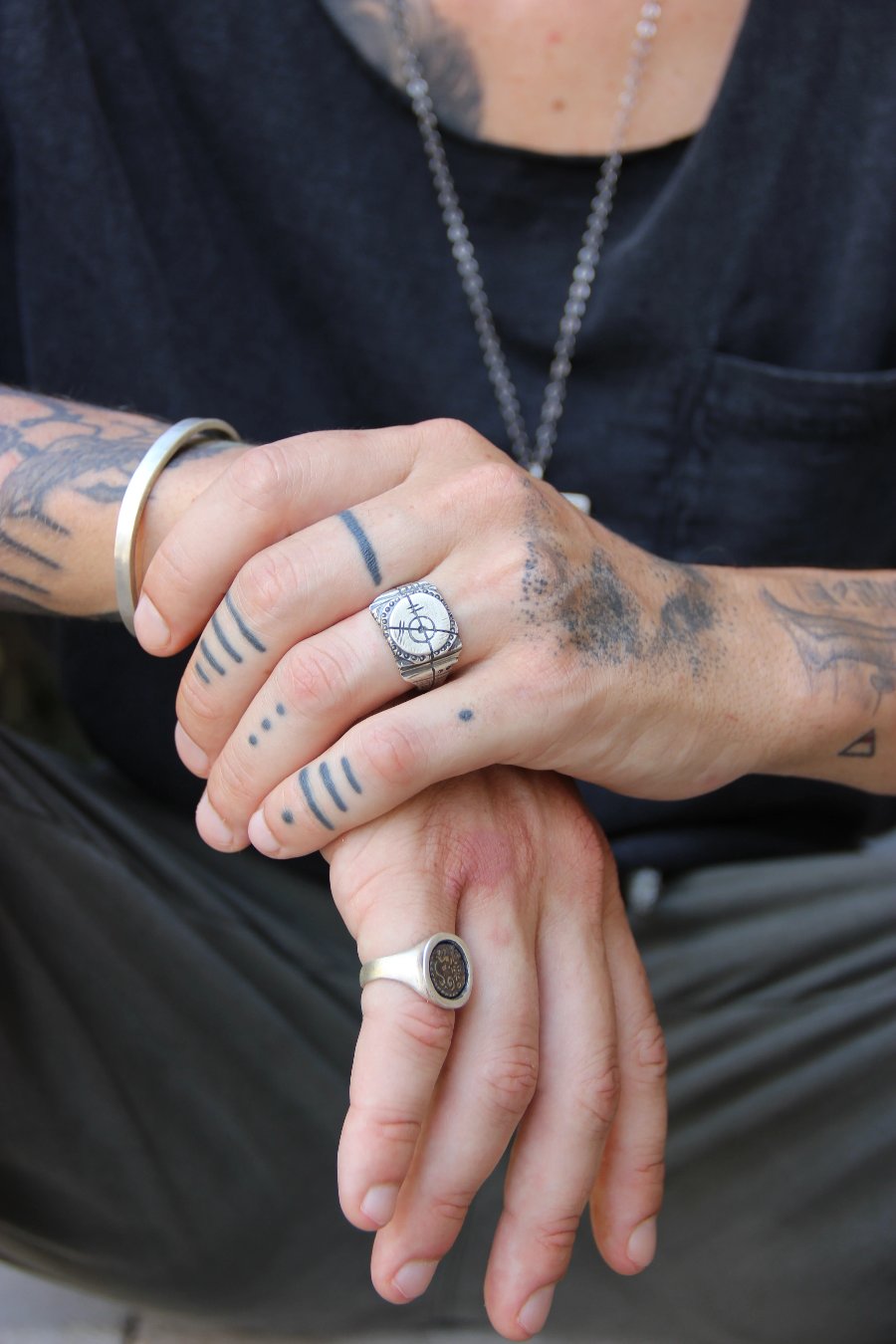 A silver ring with an oxidized and brushed finish, featuring a target design and ornamental details.