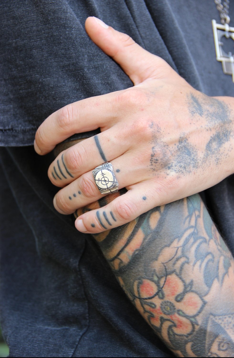 A silver ring with an oxidized and brushed finish, featuring a target design and ornamental details.