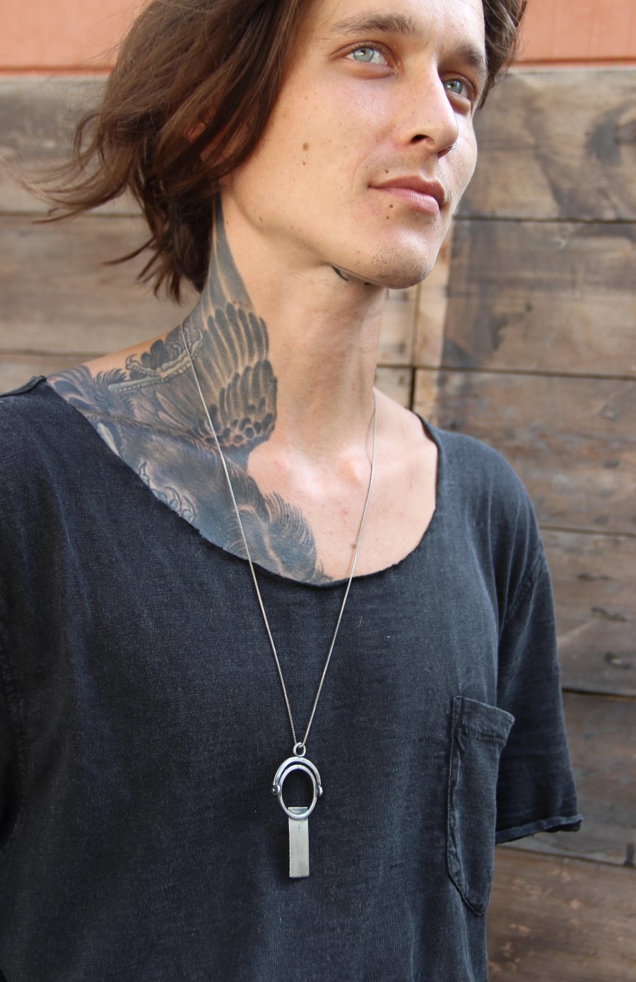 A sterling silver necklace with a magnifying glass pendant and a cross on the chain.