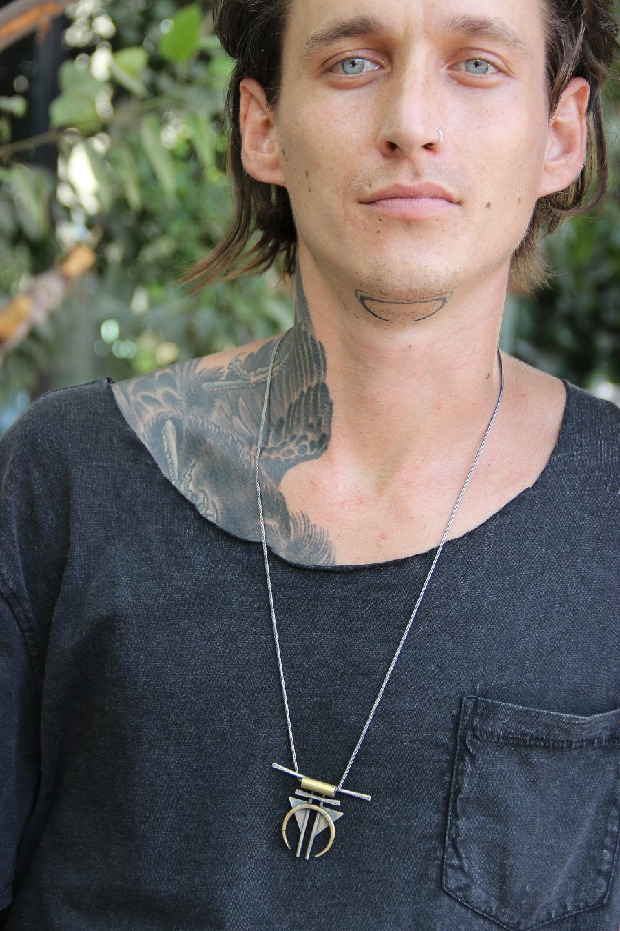 A silver and gold-colored necklace with a geometric pendant, featuring a chain and a series of geometric shaped pendants attached to it.
