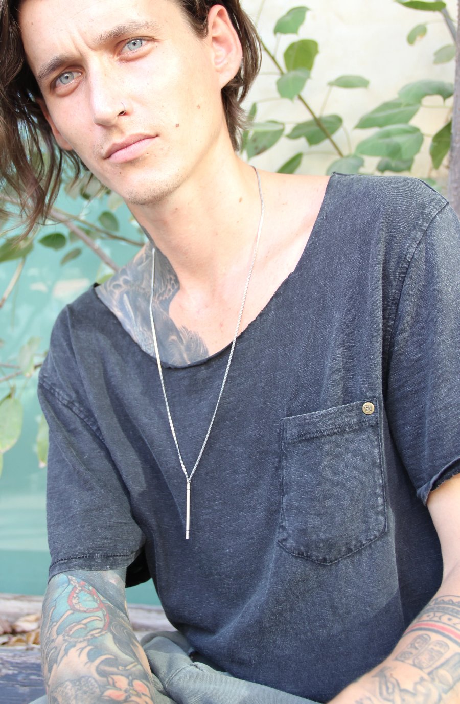 A silver necklace with a pendant resembling a stick
