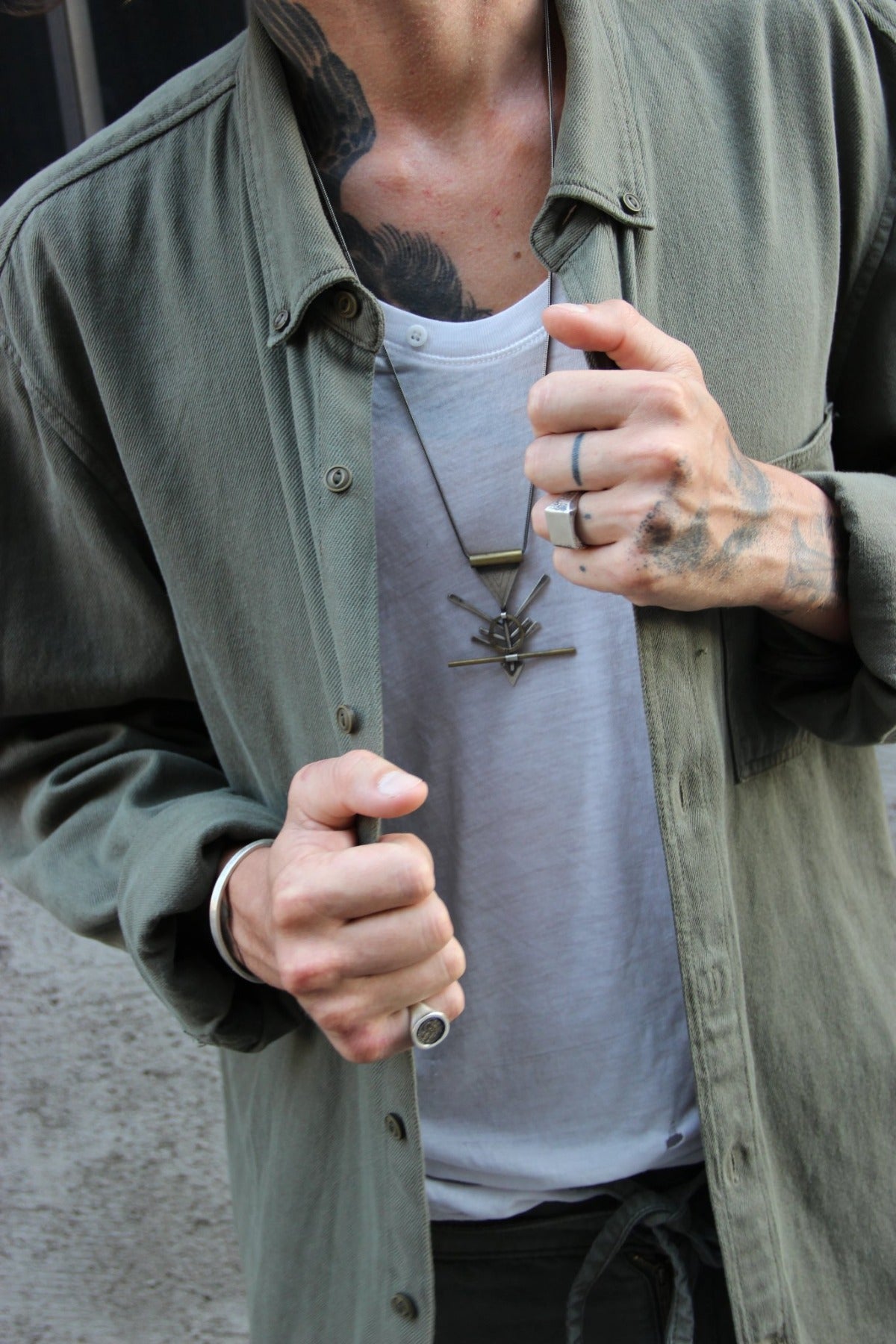 A silver and brass necklace with a geometric pendant, featuring a chain and a series of geometric shaped pendants attached to it.