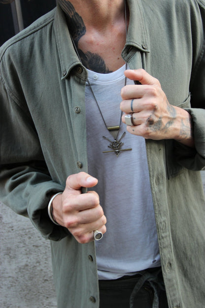 A silver and brass necklace with a geometric pendant, featuring a chain and a series of geometric shaped pendants attached to it.