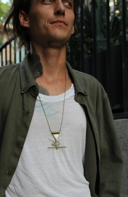 A silver and brass necklace with a geometric pendant, featuring a chain and a series of geometric shaped pendants attached to it.