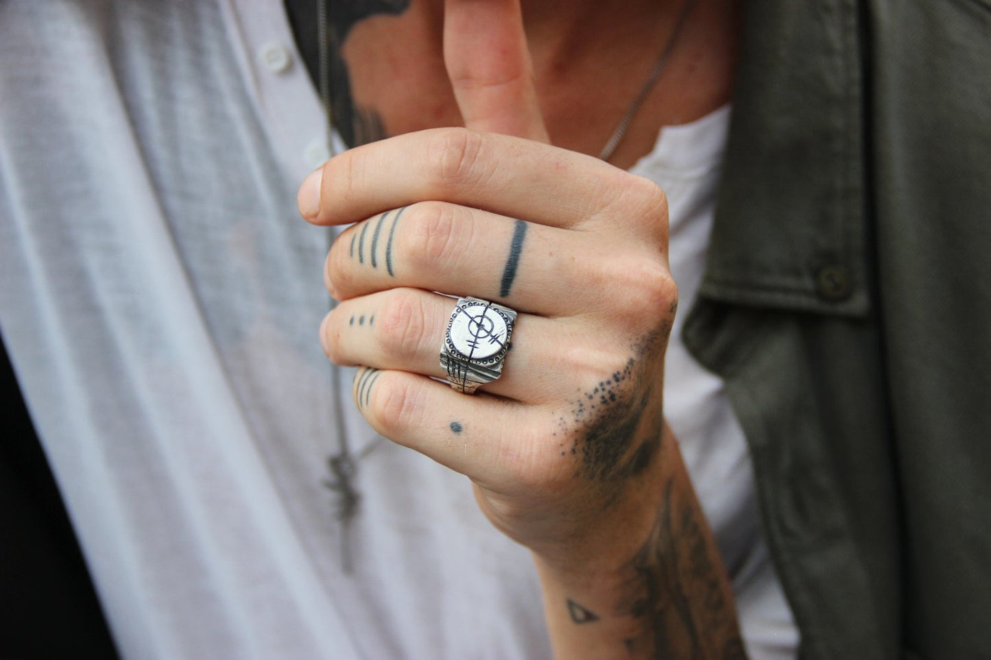 A silver ring with an oxidized and brushed finish, featuring a target design and ornamental details.