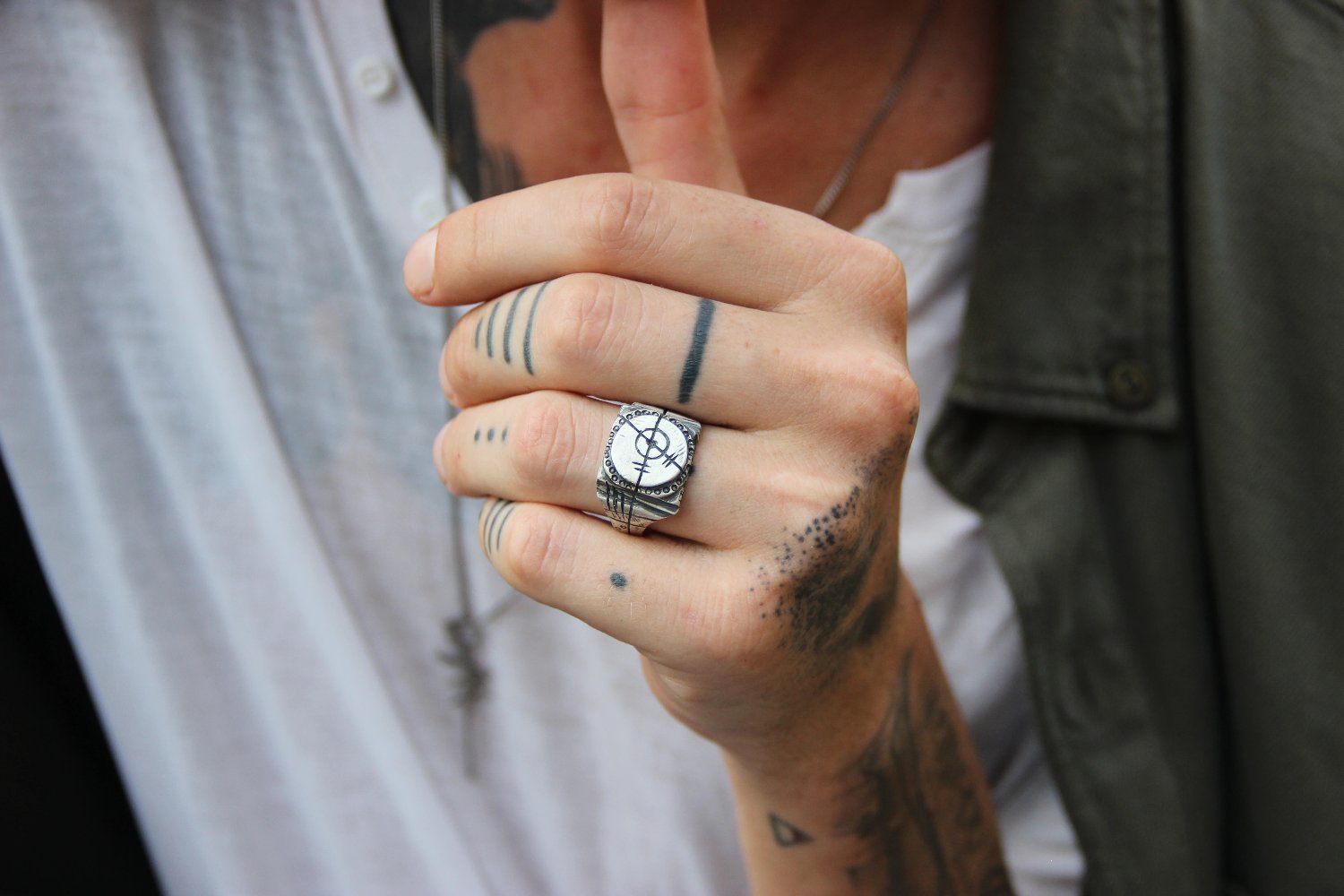 A silver ring with an oxidized and brushed finish, featuring a target design and ornamental details.