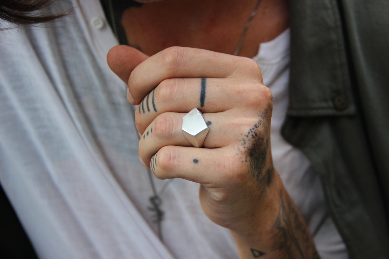 A silver ring with a geometric cutout design on the top part, with a matte finish.