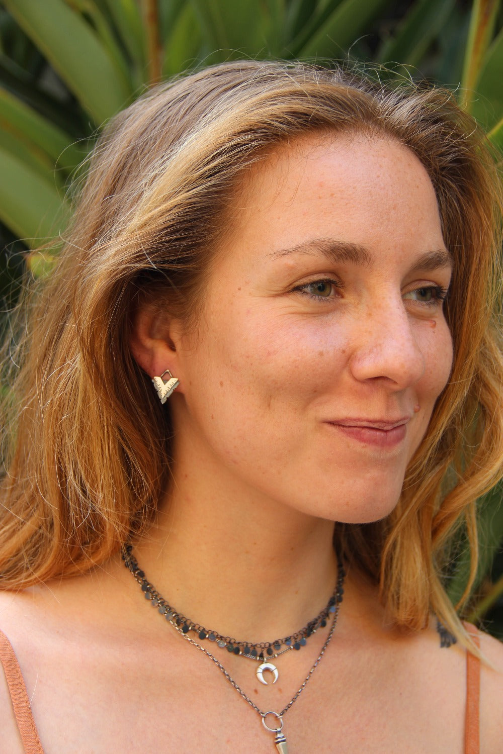 A pair of silver earrings with a geometric design, featuring a triangular shape with lines on the side