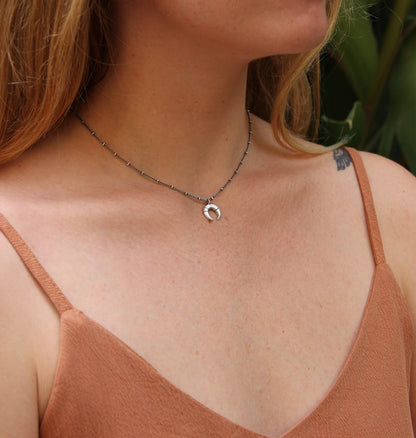 A silver necklace with a crescent-moon pendant and chain.