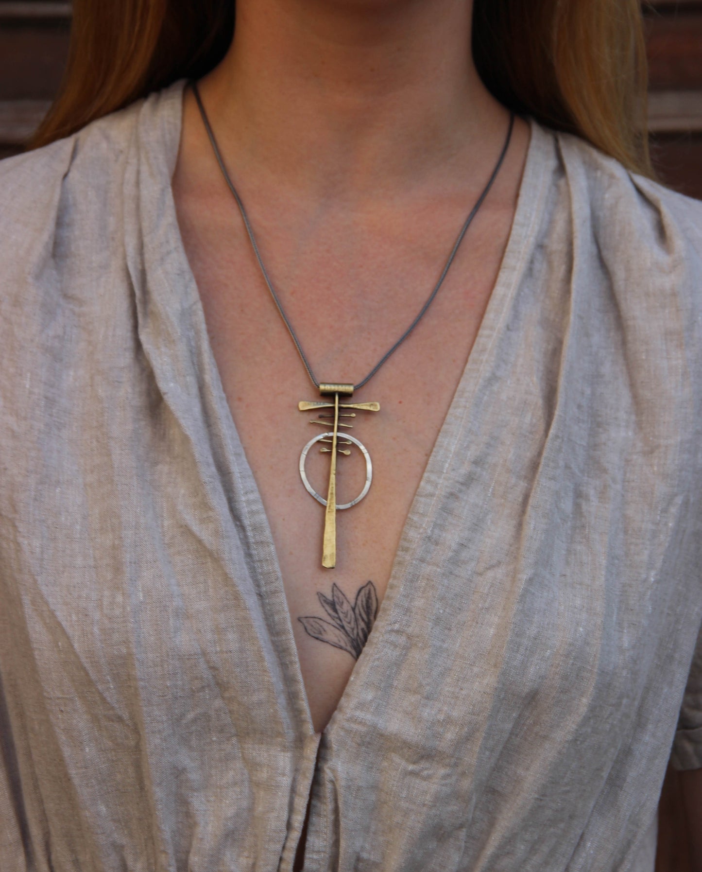 A silver and brass necklace with a geometric pendant