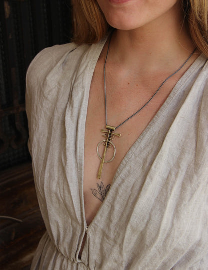 A silver and brass necklace with a geometric pendant