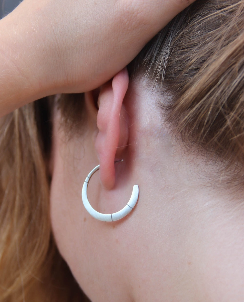 A pair of oxidized silver hoop earrings with a brushed finish