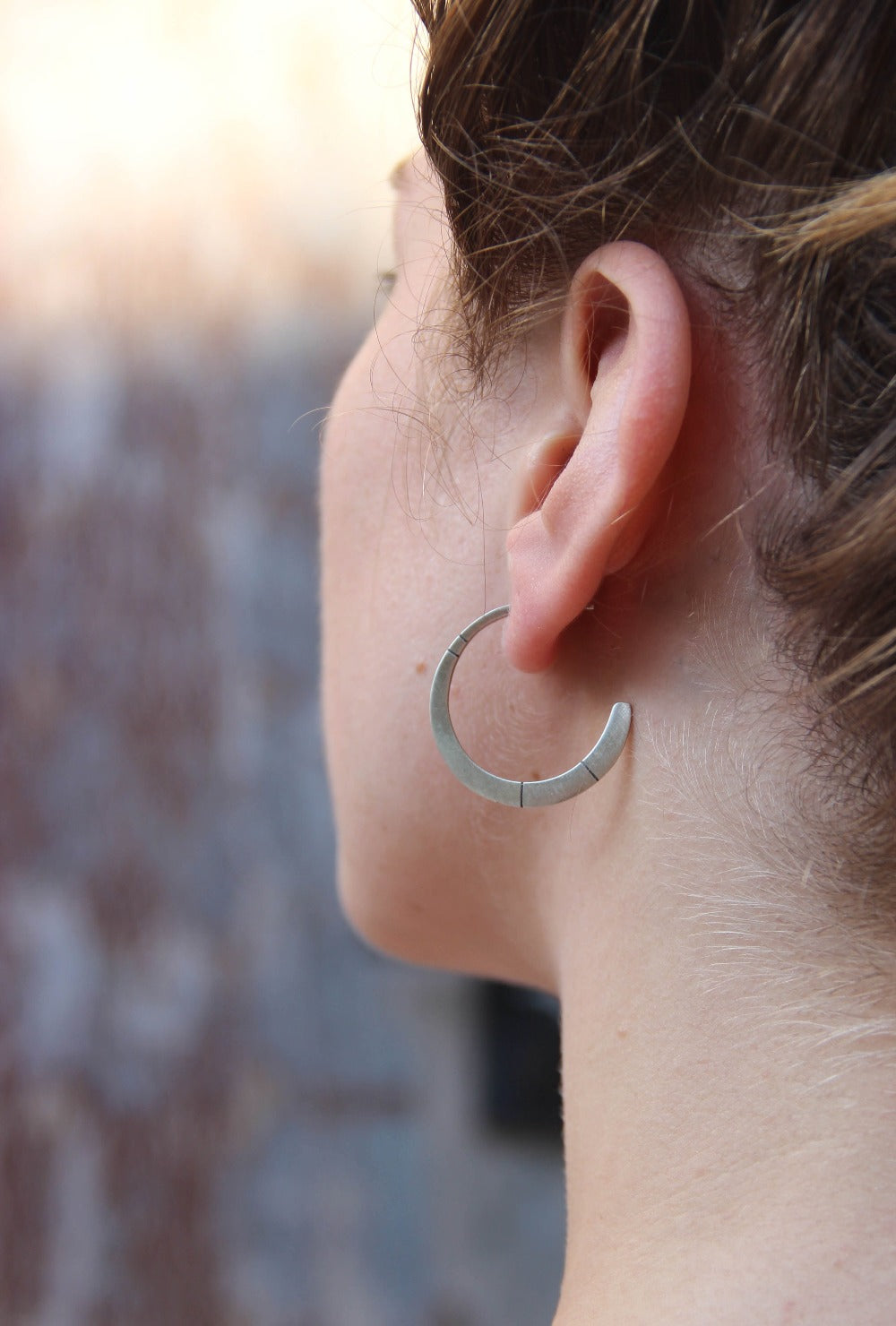 A pair of oxidized silver hoop earrings with a brushed finish