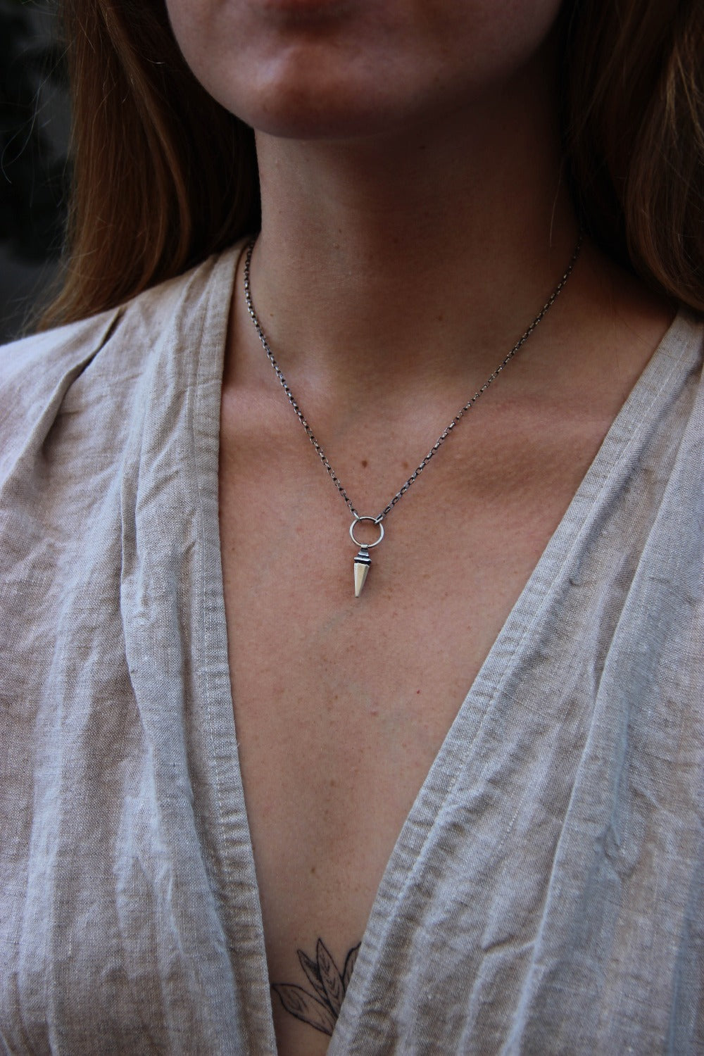 A sterling silver pendulum necklace with a brushed finish and a chain loop at the top.
