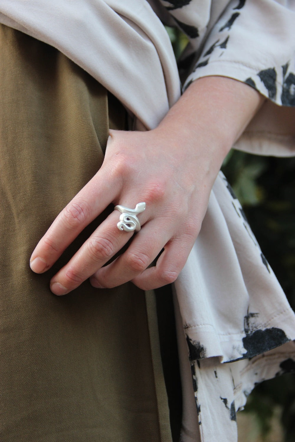 A silver ring featuring a brushed finish, handcrafted in the shape of a snake.